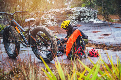 Bicycle parked on rock against plants