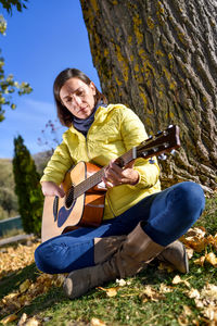 Man playing guitar on tree trunk