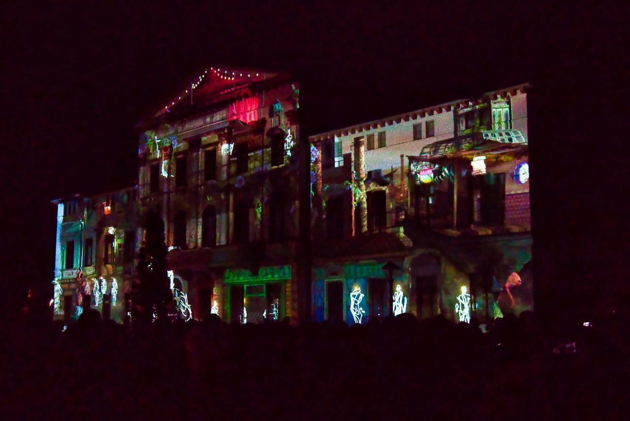 PEOPLE AT ILLUMINATED BUILDING AT NIGHT