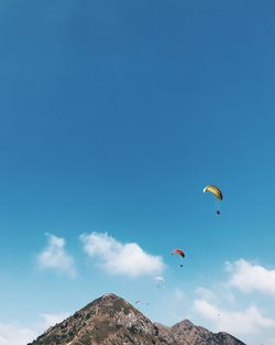 Low angle view of paragliders against blue sky