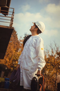 Manual worker holding cable while standing against tree