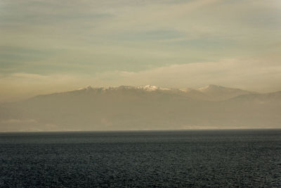 Scenic view of sea and mountains against sky