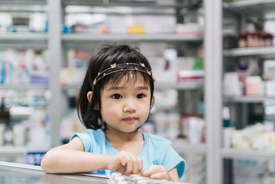 Close-up cute girl wearing tiara standing at checkout in store