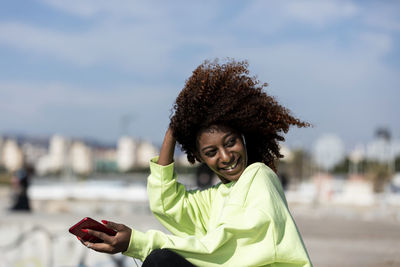 Portrait of smiling young woman using smart phone outdoors