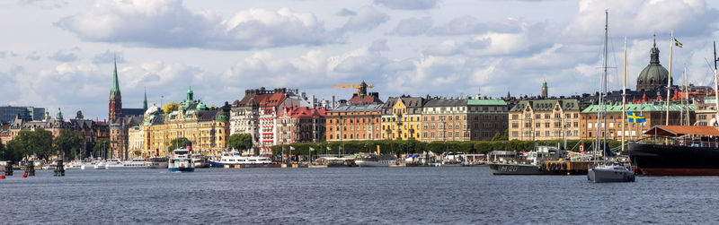 View of buildings by river against cloudy sky