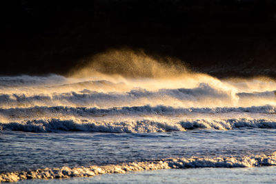 Scenic view of waves against sky during sunset