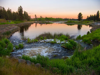 Scenic view of river against sky at sunset