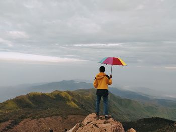 Rear view of man with umbrella against sky