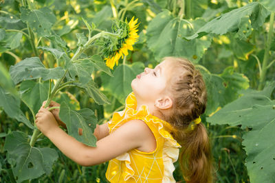 Side view of young woman holding plant