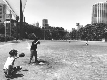 Children playing soccer in city against sky