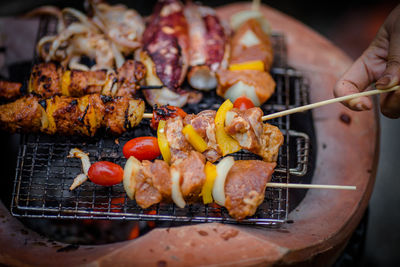 Close-up of woman holding meat on barbecue grill