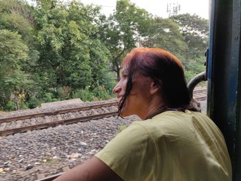 Side view portrait of mature woman sitting on railroad track