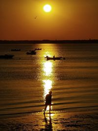 Silhouette man standing at beach against sky during sunset