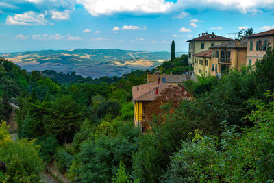 House amidst trees and buildings against sky