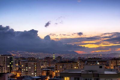 Cityscape against cloudy sky during sunset