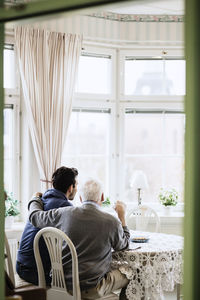 Rear view of caretaker with elderly man in nursing home