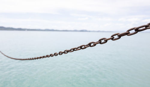 Close-up of chain on lake against sky