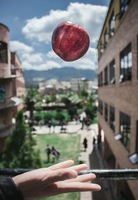 Close-up of hand holding city against sky