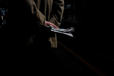 Midsection of man holding a newspaper 