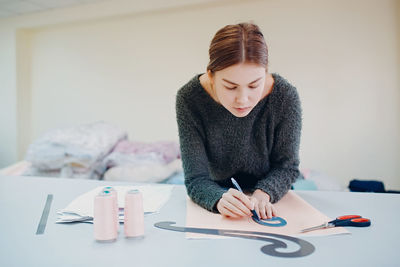 Young woman using phone while sitting on table