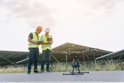 Men working at construction site against sky