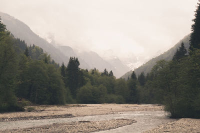 Scenic view of stream by mountains against sky