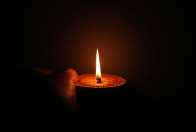 Close-up of lit candle in the dark