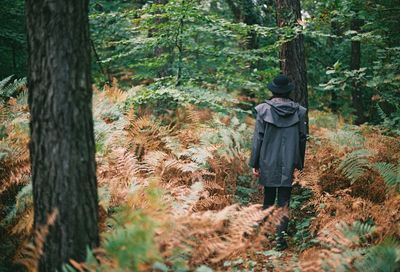 Man standing by trees in forest