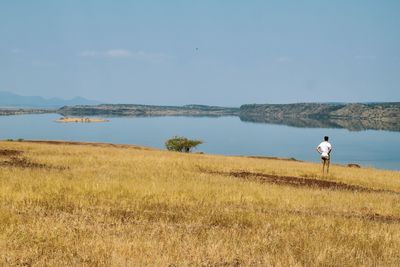 A man standing at a lake against sky at lake magadi, kenya, rift valley