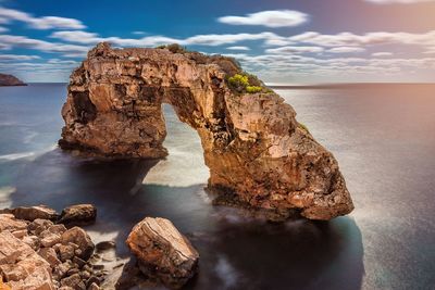 Rock formation in sea against sky