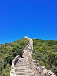 Walkway leading to built structure against clear blue sky
