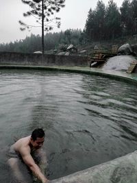 Man surfing in lake against trees