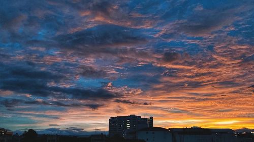 Low angle view of silhouette buildings against dramatic sky