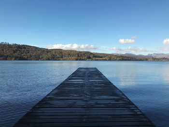 Pier over lake against blue sky