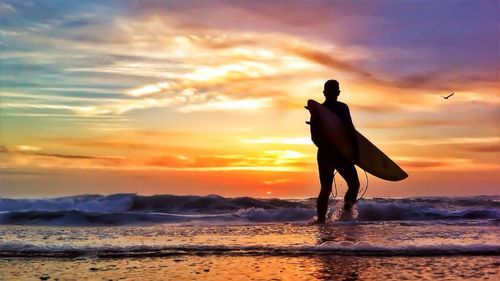 Silhouette of people on beach at sunset