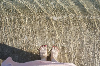 Low section of woman standing in sea