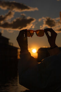 Optical illusion of silhouette woman standing against sky during sunset