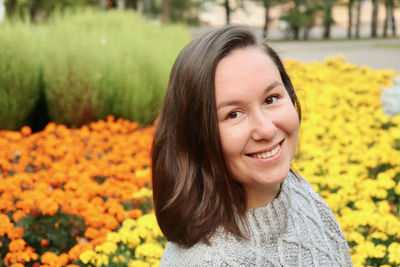 Portrait of young woman standing amidst yellow flowers