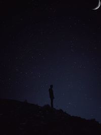 Rear view of man standing against sky at night