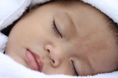 Close-up of baby sleeping on bed