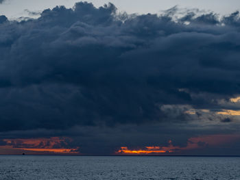 Scenic view of sea against dramatic sky during sunset