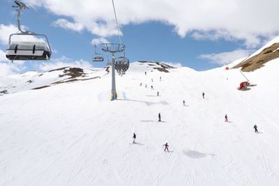 Ski lift by snowcapped mountains against sky