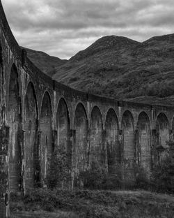 Arch bridge over mountains against sky