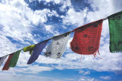 Low angle view of prayer flags hanging against sky