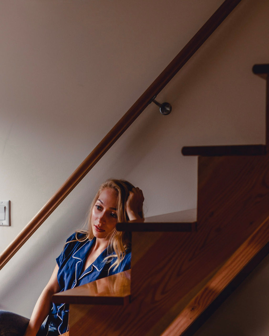 one person, real people, indoors, railing, front view, staircase, lifestyles, looking, leisure activity, young adult, young women, wall - building feature, sitting, low angle view, steps and staircases, looking away, portrait, architecture, ceiling, contemplation