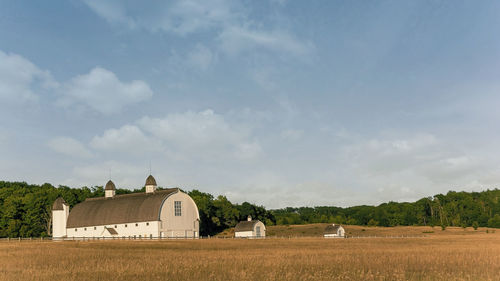 Scenic view of field by buildings against sky