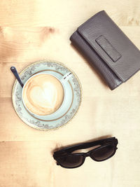 High angle view of coffee with wallet and sunglasses on table