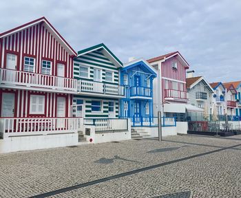 Houses on beach by buildings against sky