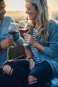 Couple sitting with wine against sky