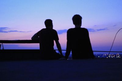 Silhouette people looking at sea against sky